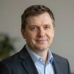 Портрет уверенного российского бизнесмена с дружелюбным взглядом на размытом нейтральном фоне в студии