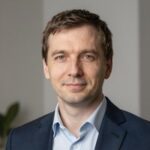 Портрет уверенного российского бизнесмена с дружелюбным взглядом на размытом нейтральном фоне в студии